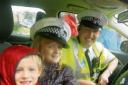 We’re the police: Abigail and Benjamin Sutton in a police car with Al Cuthbertson.