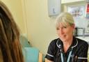 Sharon Dines hands Tamiflu to a flu friend at Leigh Primary Care Centre