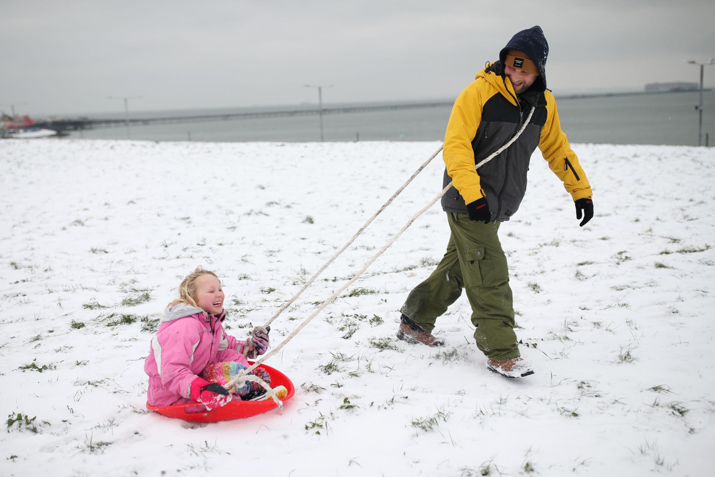 Daniel Smith with his daughter Betty, aged 7, playing on the snow-covered seafront at Southend. Picture: Yui Mok/PA Wire