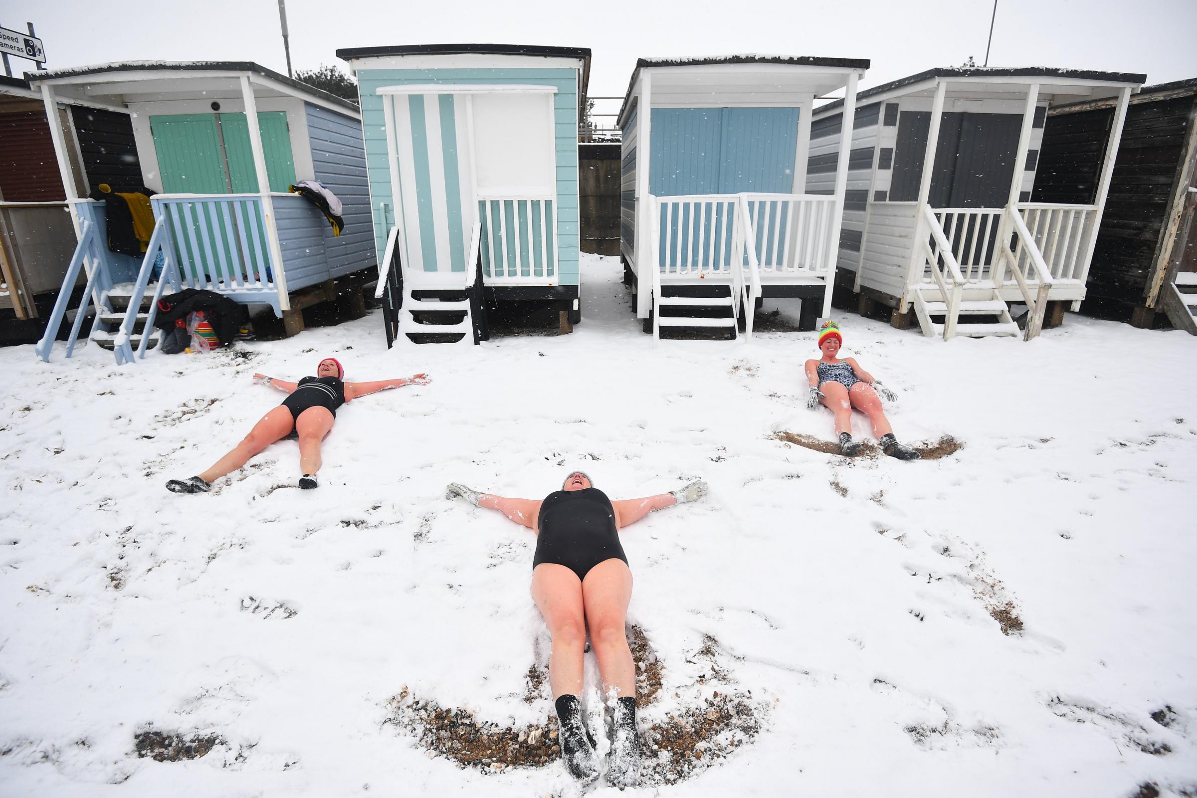 Swimmers (left to right) Sallyann Manthorp, Peta Hunter and Victoria Carlin make angels in the snow. Picture: Victoria Jones/PA Wire 
