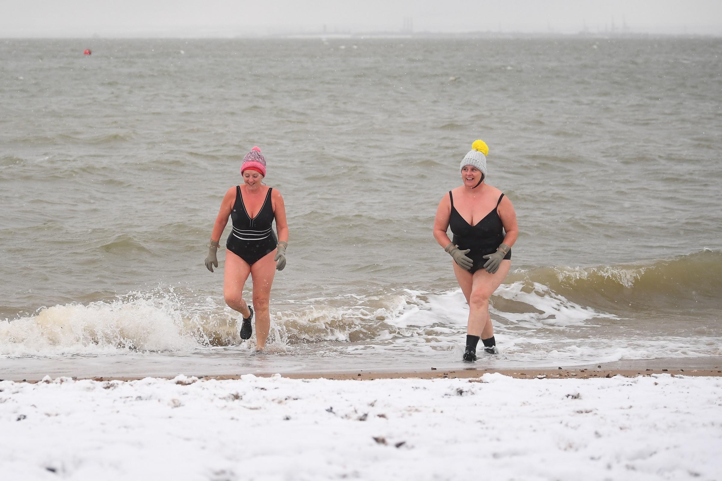 Early morning swimmers Sallyann Manthorp and Peta Hunter walk out of the water onto a snow covered beach. Picture: Victoria Jones/PA Wire 