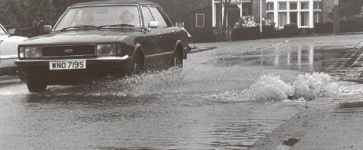 Flooding - a car slowly meanders through Station Road, Westcliff, in 1981
